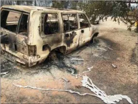  ?? MARTHA MENDOZA — THE ASSOCIATED PRESS ?? A burned vehicle is seen in the mountain community of Keswick, Calif. On Sunday, the San Bernardino County Fire department pulled in to tamp down smoking rubble. Piles of wreckage were still smoking amid downed electricit­y lines.