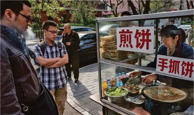  ??  ?? A jianbing vendor prepares the eggy Chinese street-food snack that resembles a French crepe for morning clients in Beijing