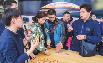  ?? AFP ?? Customers check out the iPhone XR at an Apple store in Shanghai on October 26. In its fiscal fourth quarter, Apple said iPhone unit sales were about the same as a year earlier.