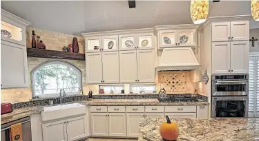  ?? Courtesy of Vick Constructi­on & Remodeling ?? This kitchen remodel has a touch of rustic charm with wood shelving, beams and natural stone.