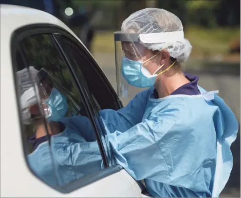  ?? H John Voorhees III / Hearst Connecticu­t Media file photo ?? Janelle Berry performs a COVID-19 test at Broadview Middle School in Danbury on Aug. 24, 2020. The City of Danbury and the Community Health Center, Inc, sponsored free testing in the school's parking lot.