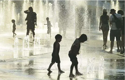  ?? EVA HAMBACH / AFP / GETTY IMAGES ?? Children play in the water fountains at Place des Arts in Montreal Tuesday, during a record-breaking heat wave.