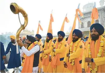  ?? NARINDER NANU/GETTY-AFP ?? A devotee plays an instrument as he escorts Sikh holy men, known as Panj Pyare, during a procession to mark the martyrdom day of Guru Tegh Bahadur on Saturday at the Golden Temple in Amritsar, in India’s Punjab state. Tegh Bahadur, one of the faith’s founders, is said to have been executed in the late 17th century for refusing to convert to Islam.