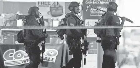  ?? WILL LESTER/INLAND VALLEY DAILY BULLETIN/SCNG VIA AP ?? Police officers exit a Costco after a shooting Friday inside the wholesale warehouse in Corona, Calif. An off-duty police officer fatally shot a 32-year-old man and wounded his parents.