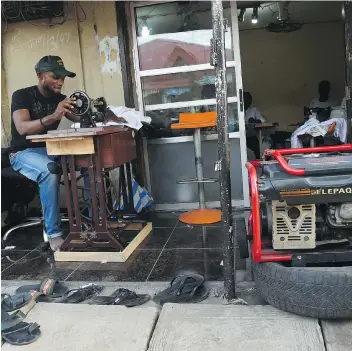  ?? UTOMI EKPEI/GETTY IMAGES ?? Like many Nigerians, this tailor is forced to use a small generator for power. One entreprene­ur saw this problem as an opportunit­y and started a company that leases hybrid solar batteries.