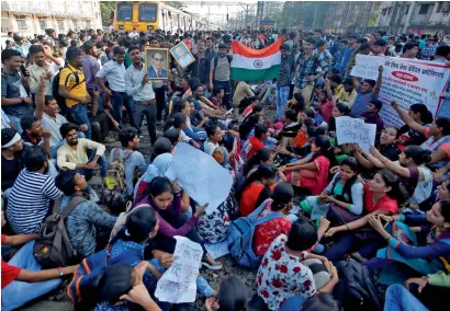  ?? Reuters ?? People sit on tracks as they block train services during a protest demanding recruitmen­t into the railway services in Mumbai. —