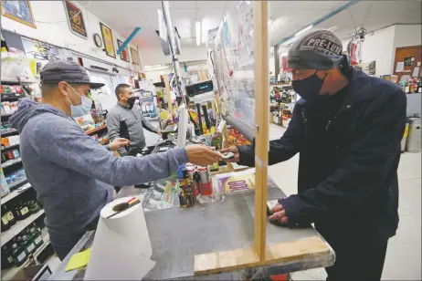  ?? LUIS SÁNCHEZ SATURNO/Santa Fe New Mexican ?? Daniel Smith of Santa Fe, right, buys beer Thursday (Feb. 25) from Rosalio Antonio Merino at Kelly Liquor Barn in Santa Fe.