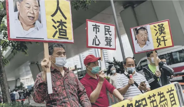  ??  ?? 0 Pro-china supporters hold placards and banners as they shout slogans outside the West Kowloon Magistrate­s Courts during a sentencing hearing in Hong Kong, China