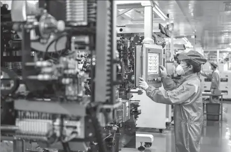  ?? TAN YUNFENG / FOR CHINA DAILY ?? Top: An employee works at a production facility of a new energy vehicle battery company in Huzhou, a green finance pilot city in Zhejiang province, in July.