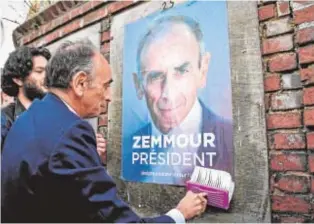  ?? // AFP ?? El derechista Éric Zemmour pega un cartel de su candidatur­a
