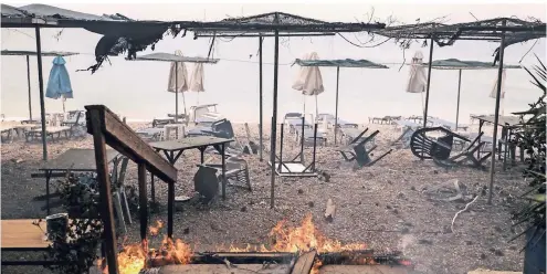  ?? FOTO: DPA ?? Verbrannte Strandmöbe­l stehen am Strand von Kineta in der Nähe Athens. Zwei große Waldbrände sind am Montag außer Kontrolle geraten.