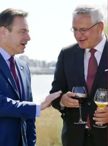  ?? FOTO ISOPIX ?? “Houd mijn glas even vast, anders kan ik geen hand geven”, grapt burgemeest­er Bart De Wever tegen Kris Peeters. Geen uur na de persconfer­entie over Aron Berger was het al lachen geblazen tussen de Antwerpse kopstukken van N-VA en CD&V.