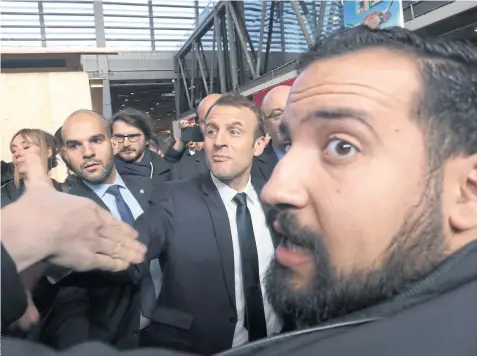  ??  ?? OUTA MY WAY: French president Emmanuel Macron, centre, as his guard Alexandre Benalla, right, looks on.