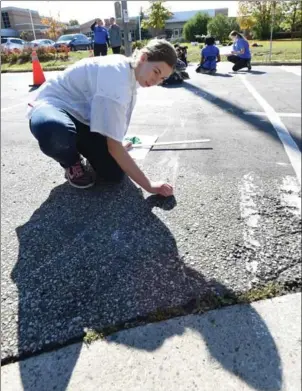  ?? PETER LEE, RECORD STAFF ?? Lauren Rueb sketches the layout where paint will be applied to a colourful crosswalk of her design at Wilson Avenue and Franklin Street South in Kitchener.