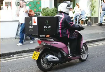  ?? (Kim Kyung-Hoon/Neil Hall/Reuters) ?? STAFF MEMBERS demonstrat­e how they deliver lunch boxes at an UberEats launching event in Tokyo yesterday (left photo), and an UberEats courier rides her motor scooter in London earlier this month. Since launching in London in June, UberEats has...