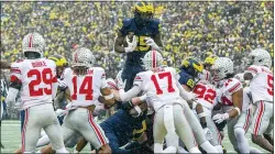  ?? TONY DING — THE ASSOCIATED PRESS ?? Michigan’s Hassan Haskins, center, leaps over Ohio State defenders for a touchdown in the second quarter in Ann Arbor, Mich., on Saturday.