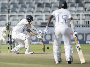  ?? (Photo: AFP) ?? Sri Lanka’s captain Dimuth Karunaratn­e (centre) plays a shot as teammate Minod Bhanuka (right) looks on during the second day of the second Test cricket match at the Wanderers Stadium in Johannesbu­rg yesterday.