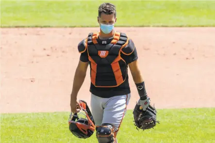  ?? Jessica Christian / The Chronicle ?? Catcher Buster Posey wears a mask of a different kind during the Giants’ summer training camp session at Oracle Park.