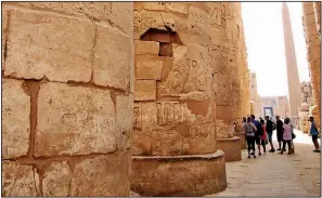  ??  ?? Massive columns tower over visitors in the Karnak Temple complex, where celebratio­ns honored Amun, an Egyptian god of life.