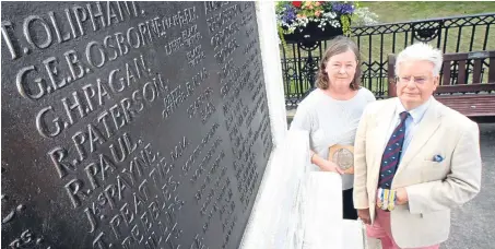  ?? Picture: Kris Miller. ?? Bill Pagan and his wife Gilli at Cupar War Memorial next to the name of his uncle George Pagan and relation George Osborne. They are holding George Pagan’s medals and dead man’s penny.