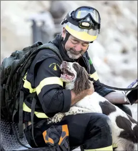  ?? AP/ MASSIMO PERCOSSI ?? A fi refi ghter cuddles his dog Monday as others search through rubble from last week’s earthquake in Amatrice, Italy. The quake killed hundreds of people, and several bodies are believed to still be buried.