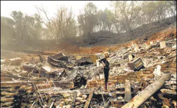  ?? AP ?? Pam, who declined to give a last name, examines the remains of her partner's Vacaville, California, home. The residence burned as the LNU Lightning Complex fires ripped through the area.