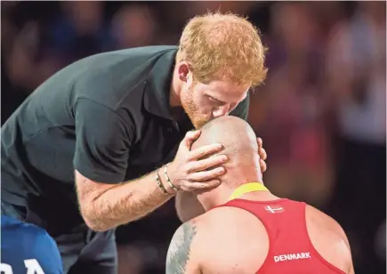  ?? GEOFF ROBINS, AFP/GETTY IMAGES ?? Prince Harry kisses the head of wheelchair rugby gold medalist Maurice Manuel of Denmark at the Invictus Games in 2017.