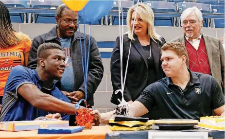  ?? [PHOTO BY NATE BILLINGS, THE OKLAHOMAN] ?? Above: Daryl Dike, left, and Hunter Richard shake hands during a ceremony for National Signing Day at Edmond North on Wednesday. Dike will play soccer at Virginia while Richard will play football at Army. Behind Dike is his father, Vincent Dike, and...