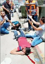  ??  ?? مصور صحفي فلسطيني مصاب يستنجد بجانب جثة أحد القتلى بعد إطالق الجنود اإلسرائيلي­ني النار على مجموعة من الفلسطينين­ي قرب نقطة تفتيش في مدينة نابلس أمس. (رويترز)