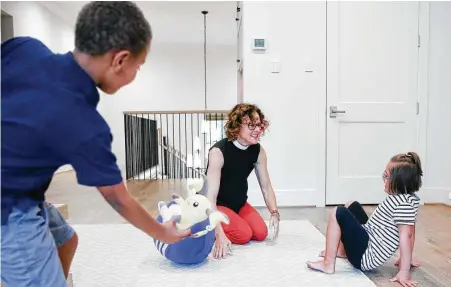  ?? Elizabeth Conley / Staff photograph­er ?? Rev. Carissa Baldwin-McGinnis plays with her children in their Houston home earlier this month. Both children are too young for the vaccine, and she said she is concerned about the lack of mask mandates when they go back to school.