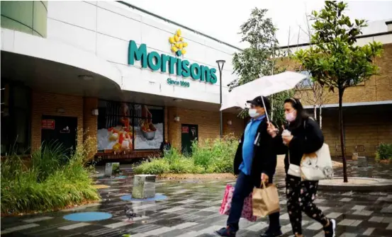  ?? AFP/VNA Photo ?? People walk past a Morrisons supermarke­t in Stratford, east London.