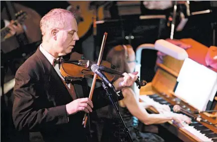  ?? ERIN HOOLEY/CHICAGO TRIBUNE ?? Columnist Eric Zorn plays the violin while columnist Mary Schmich plays piano during a 2015 performanc­e of Songs of Good Cheer.