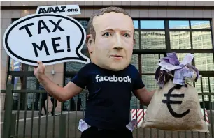  ??  ?? An activist wearing a mask depicting Facebook’s CEO Mark Zuckerberg demonstrat­es during the European Union finance ministers meeting, outside the EU headquarte­rs in Brussels on Tuesday.