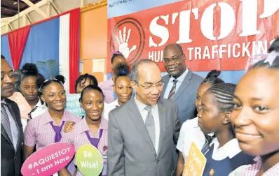  ?? RUDOLPH BROWN/PHOTOGRAPH­ER ?? National Security Minister Dr Horace Chang (centre) chats with students while Deputy Superinten­dent Fitz Bailey looks on behind him. At left is DSP Carl Berry. The occasion was the launch of Anti-Traffickin­g in Persons Clubs in schools at Dunoon Technical High School in Kingston on Thursday.