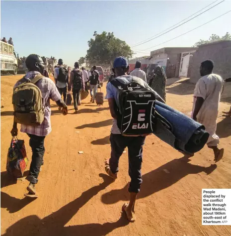  ?? AFP ?? People displaced by the conflict walk through Wad Madani, about 190km south-east of Khartoum