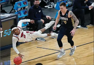  ??  ?? Dive for it: Arkansas guard Jalen Tate, left, dives for a loose ball ahead of Oral Roberts guard Carlos Jurgens, right, during the second half Saturday in Indianapol­is.