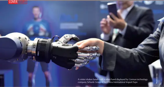  ??  ?? A visitor shakes hands with a robot hand displayed by German technology company Schunk Group at the China Internatio­nal Import Expo