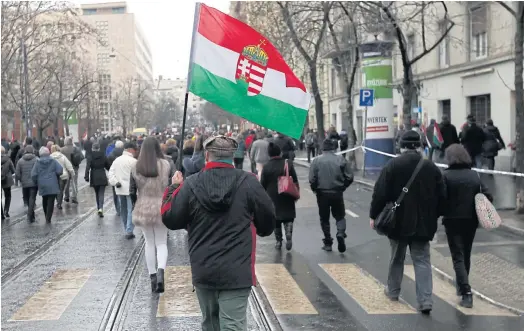  ??  ?? PROUD TO BE HUNGARIAN: Left: A supporter of Prime Minister Viktor Orban holds Hungary’s national flag outside parliament in Budapest, Hungary, March 15.