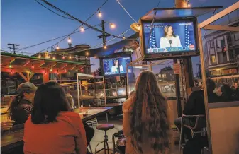  ?? Nick Otto / Special to The Chronicle ?? People watch Vice Presidente­lect Kamala Harris speak on television at Piazza Pellegrini in North Beach in San Francisco on Saturday night. Hundreds of backers celebrated in the streets.