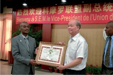  ?? PROVIDED TO CHINA DAILY ?? Professor Li Guoqiao receives the Order of the Green Cross of the Comoros from Fouad Mohadji, vice-president of Comoros.