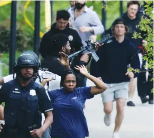  ?? (Evelyn Hockstein/Reuters) ?? CIVILIANS FLEE while a police officer trains his weapon on a nearby building at the scene of a shooting near a school in Washington DC on Friday.