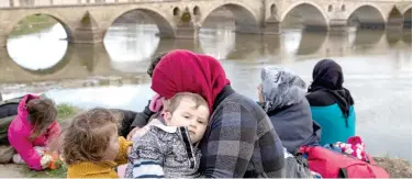  ?? Reuters ?? ↑
Migrants rest next to the Tunca river in Edirne, Turkey.