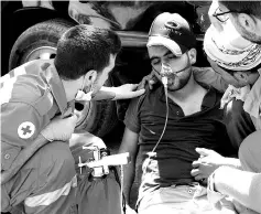  ??  ?? A man being treated for smoke inhalation by Red Cross members. — Reuters photo