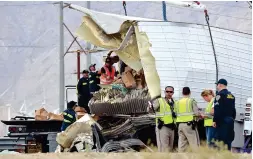  ?? THE ASSOCIATED PRESS ?? Workers remove debris from a semi-truck that crashed with a tour bus Sunday near Palm Springs, Calif. The crash killed 13 and injured 31 others. Survivors said most passengers were asleep at the time of the crash.