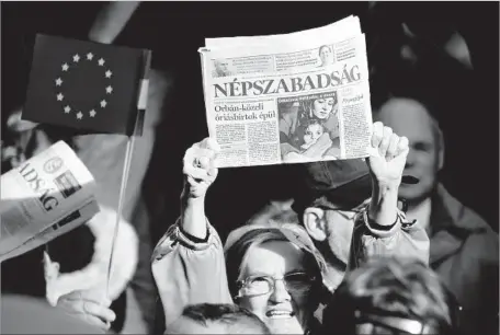  ?? Attila Kisbenedek AFP/Getty Images ?? JOURNALIST­S at Hungary’s now-closed leftist newspaper Nepszabads­ag (“Liberty of the People”) and their supporters rally in Budapest in October. The daily’s owners said it was losing money, but many Hungarians suspected the hidden hand of the right-wing...