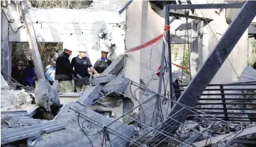  ??  ?? A general view shows emergency responders inspecting a damaged house after it was hit by a rocket in the village of Mishmeret, north of Tel Aviv. — AFP photo