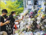  ?? Sawayasu Tsuji Getty Images ?? PEOPLE take photos of tributes in memory of the queen outside the British Consulate in Hong Kong.