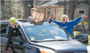  ??  ?? Cody Thurber, 5, brother Jackson, 8, and mother Coleen send birthday wishes to the Freed twins. In matching overalls, Maxwell and Riley watched the parade of cars from the sidewalk. Their mother, Amber, handed out cupcakes to passers-by with the help of a selfie stick.