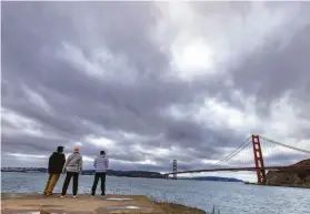  ?? John Storey / Special to The Chronicle ?? Three men look at the Golden Gate Bridge as storm clouds linger last Sunday.