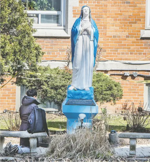  ?? PETER J THOMPSON / NATIONAL POST ?? A woman kneels before a statue Wednesday at the Lady of Assumption Parish Catholic Church
on Bathurst Street in Toronto during the COVID-19 pandemic on Wednesday.